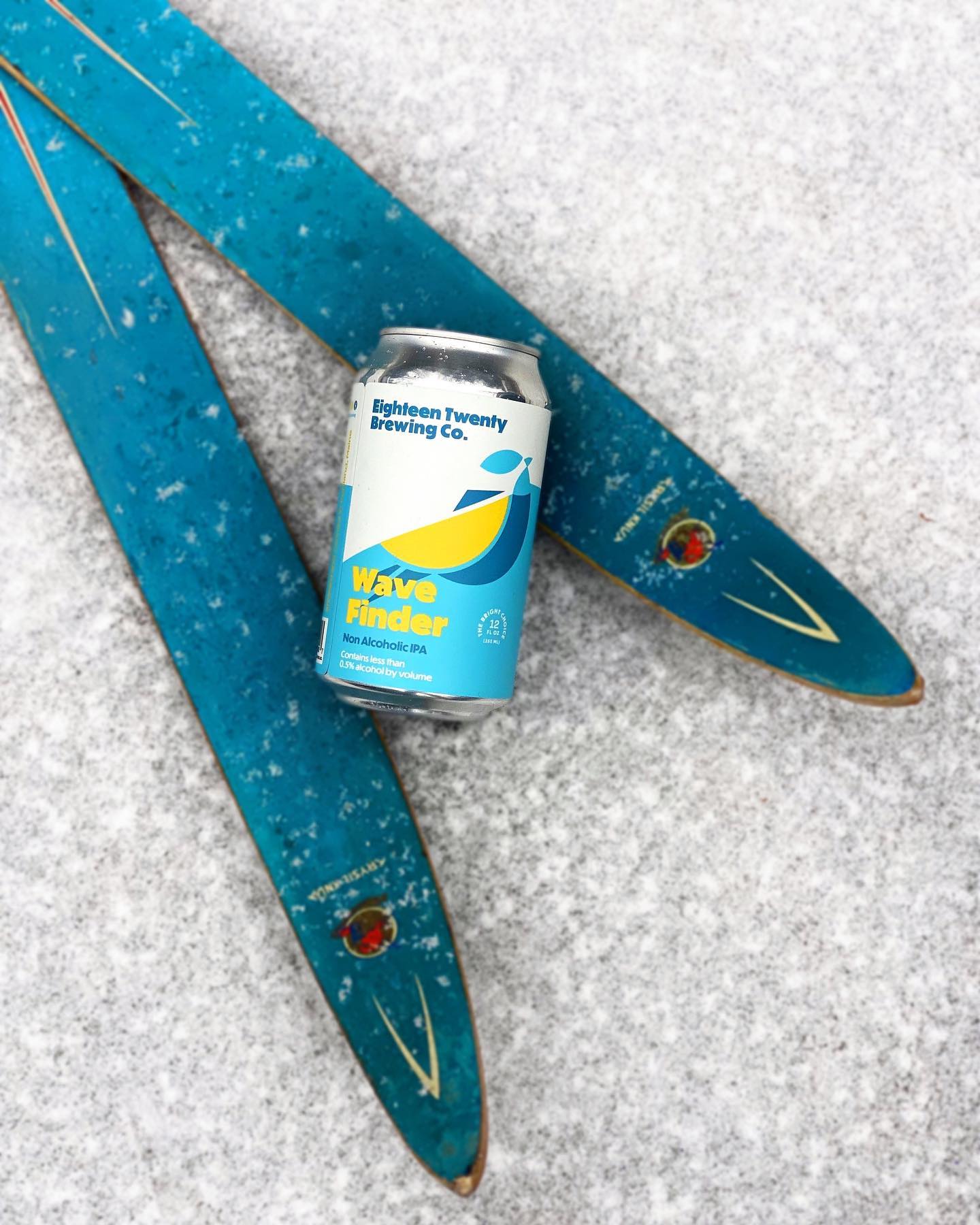 A can of Wave Finder on a pair of skis in the snow.